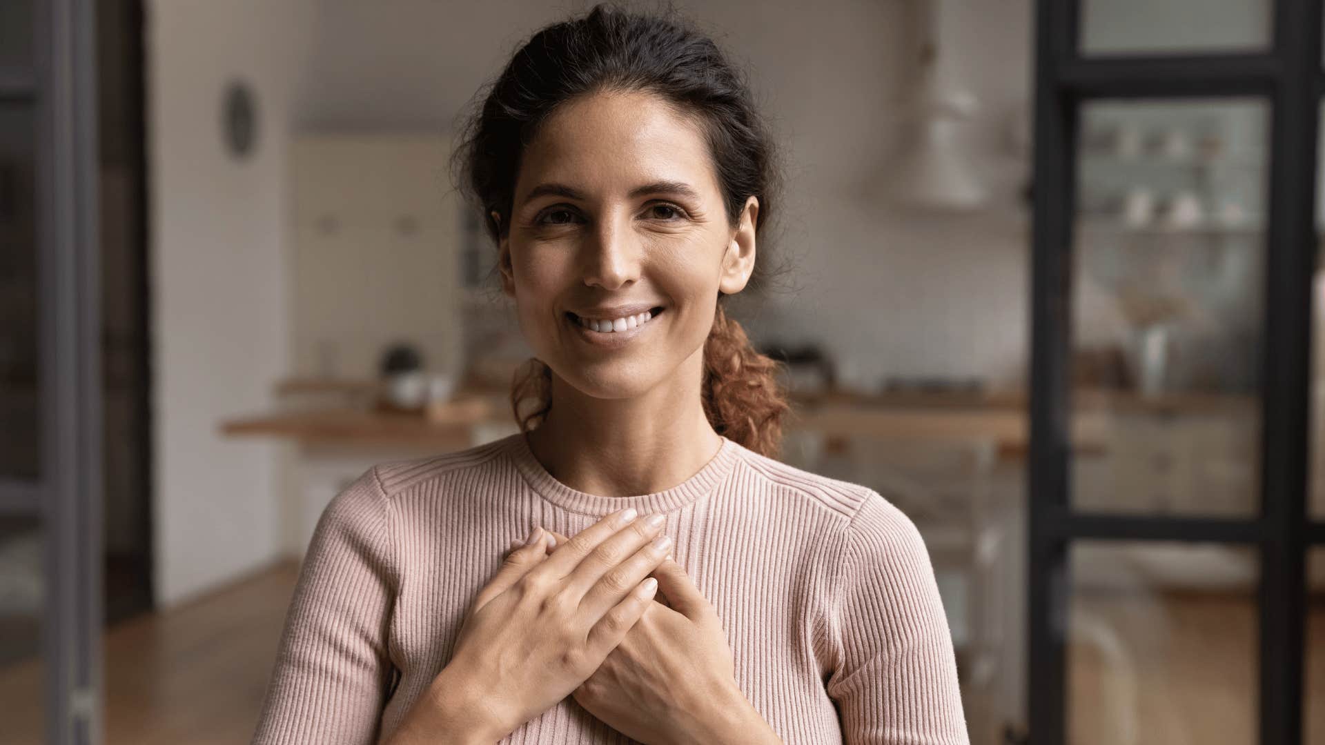 woman holding hand over heart and smiling 