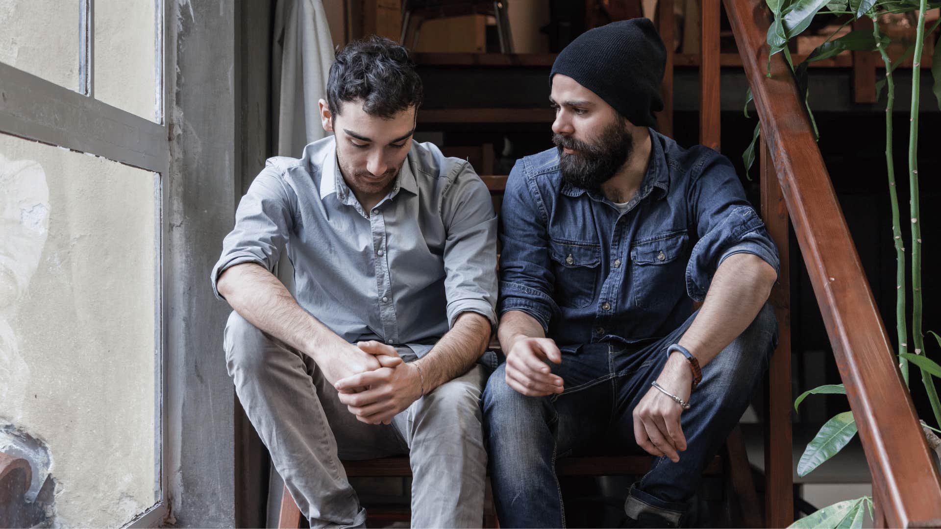 man chatting with upset friend on stairs 