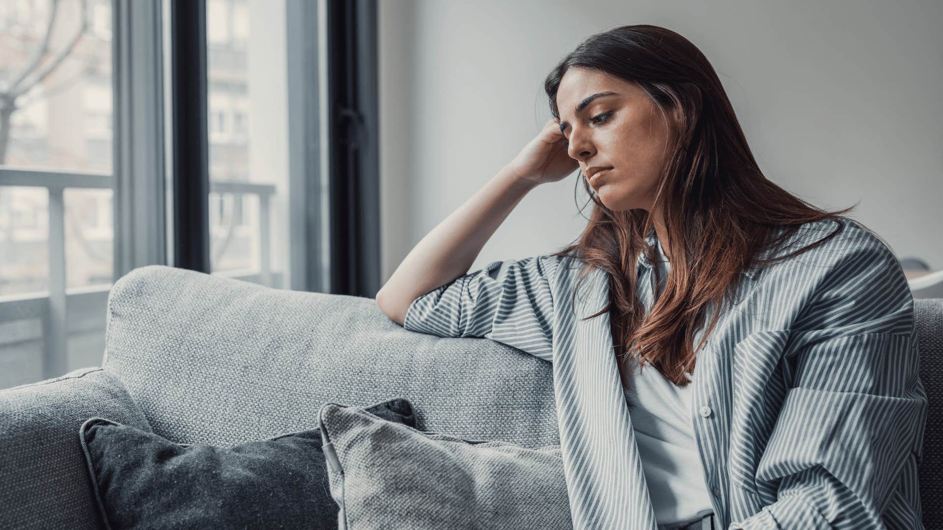 woman looking upset while sitting on couch