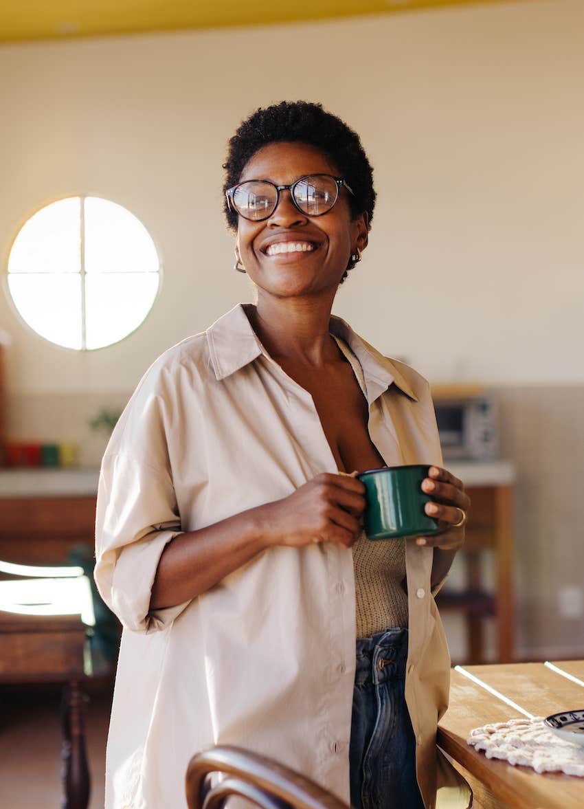 Woman smiles while holding coffee cup