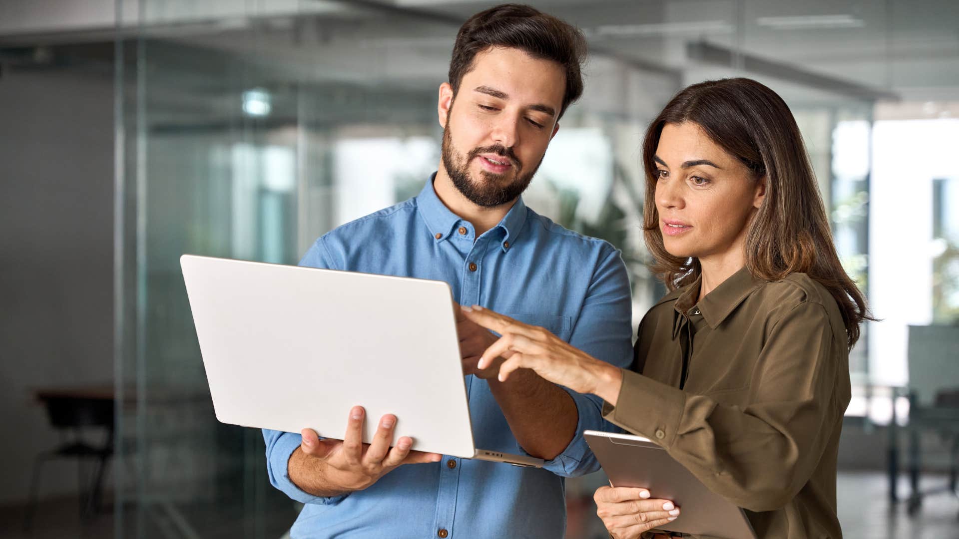 Frustrated boss talking to a worker and pointing at their laptop.