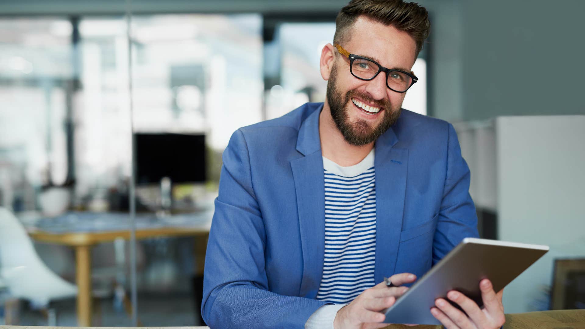 Male employee looking happy holding a tablet.