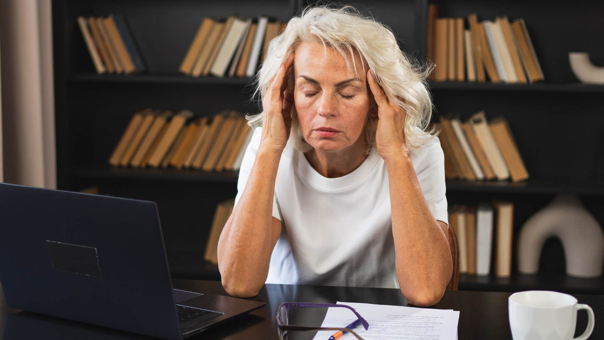 Older employee looking upset at her desk. 