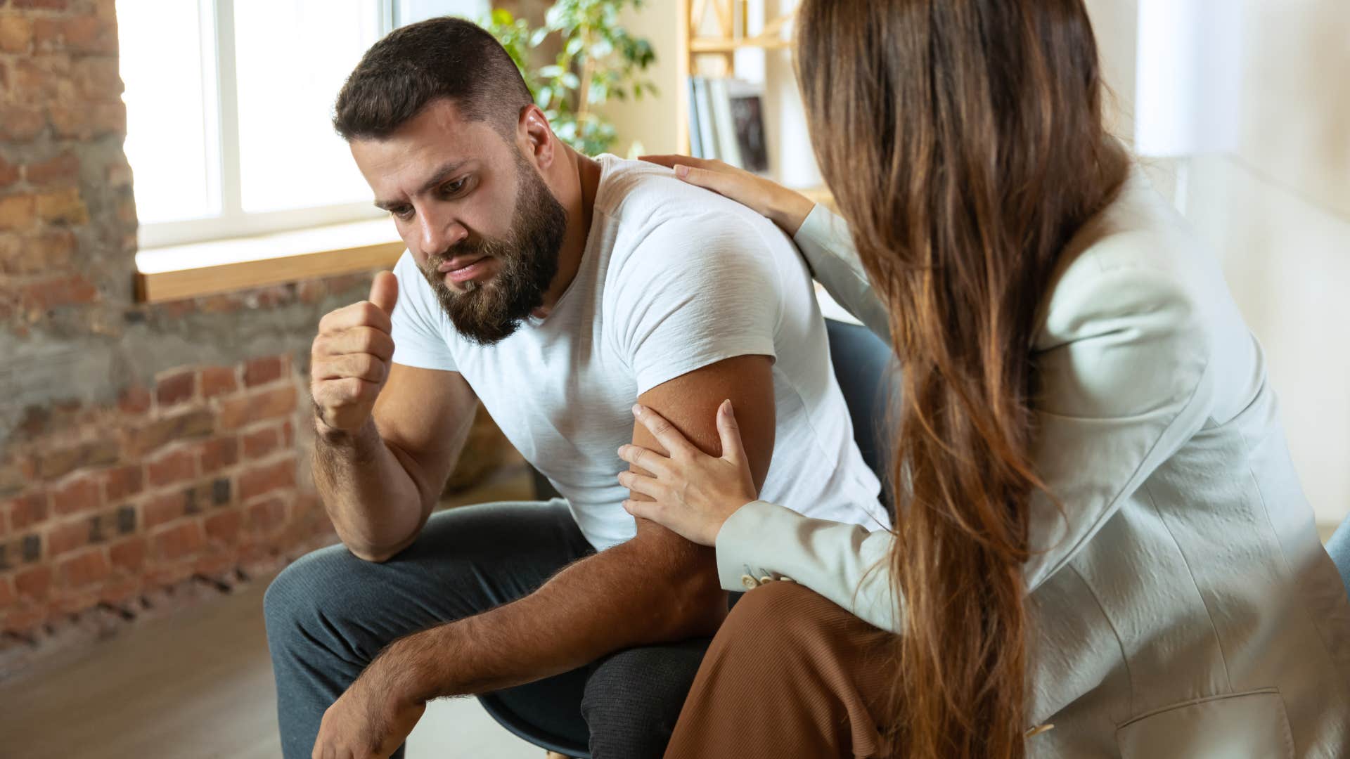 Man looking upset while a woman comforts him