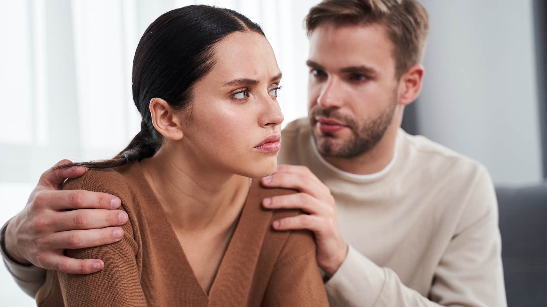 Man comforting a woman on their couch