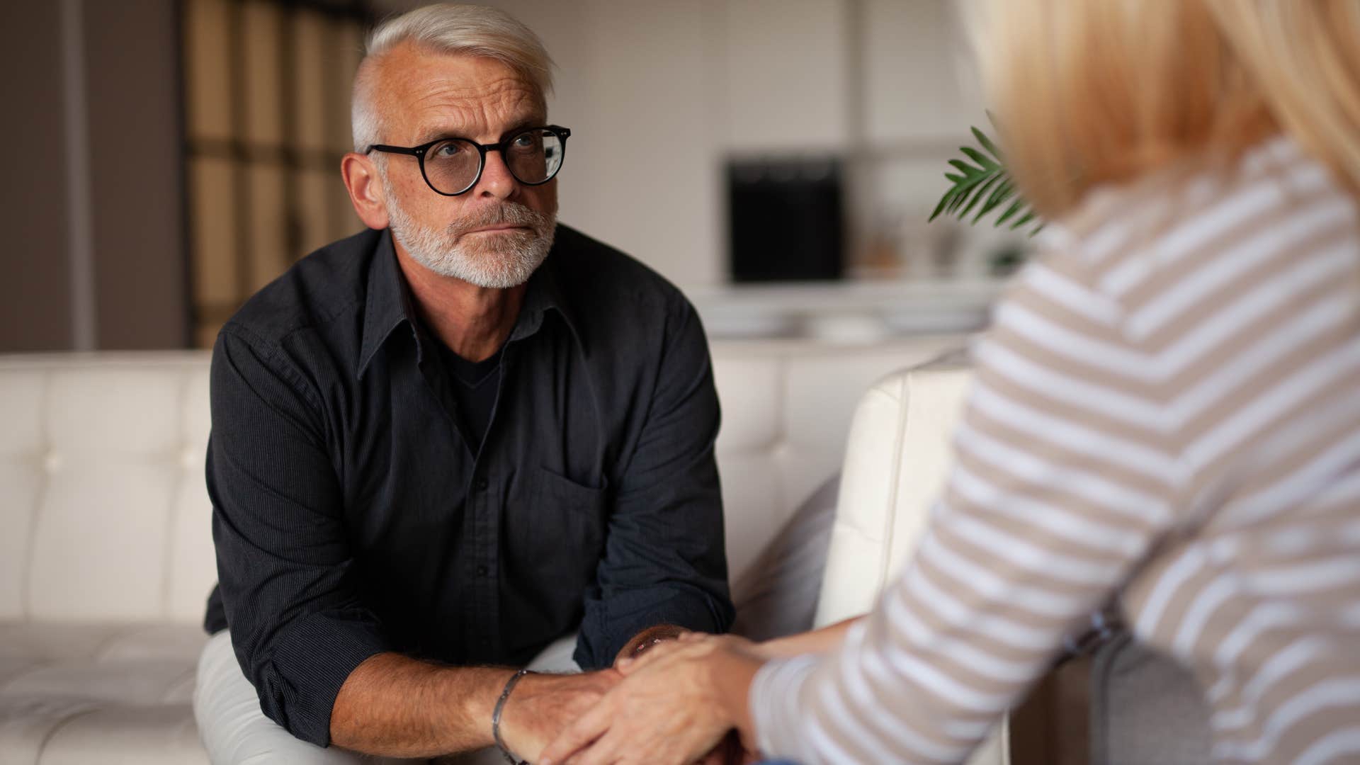 Older man looking at his wife on the couch