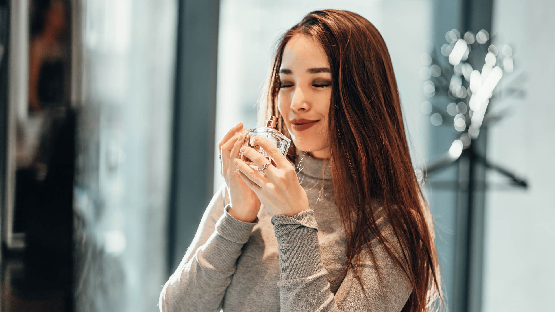 woman smelling a bottle of perfume