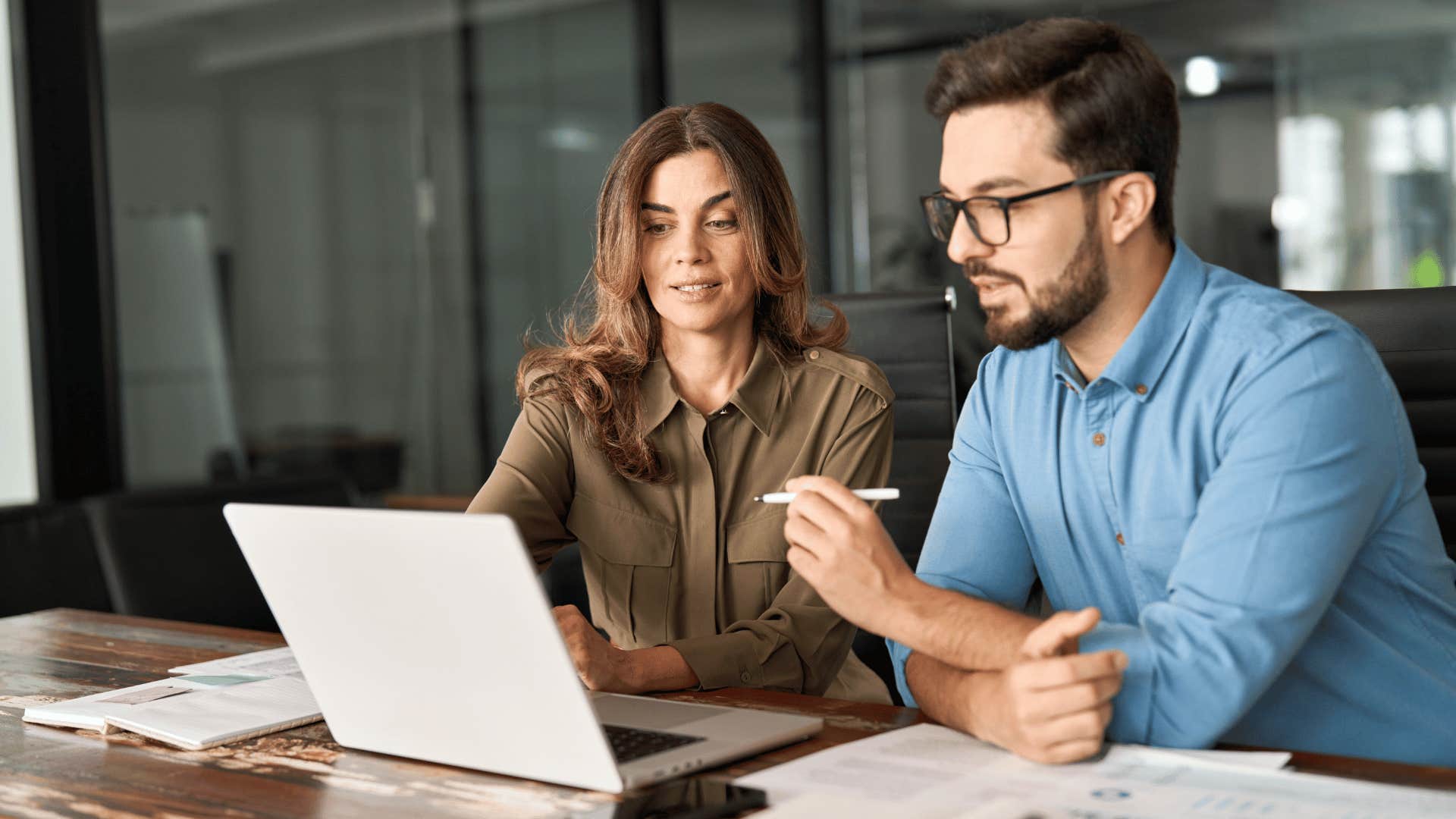 man and woman looking at laptop and working together 