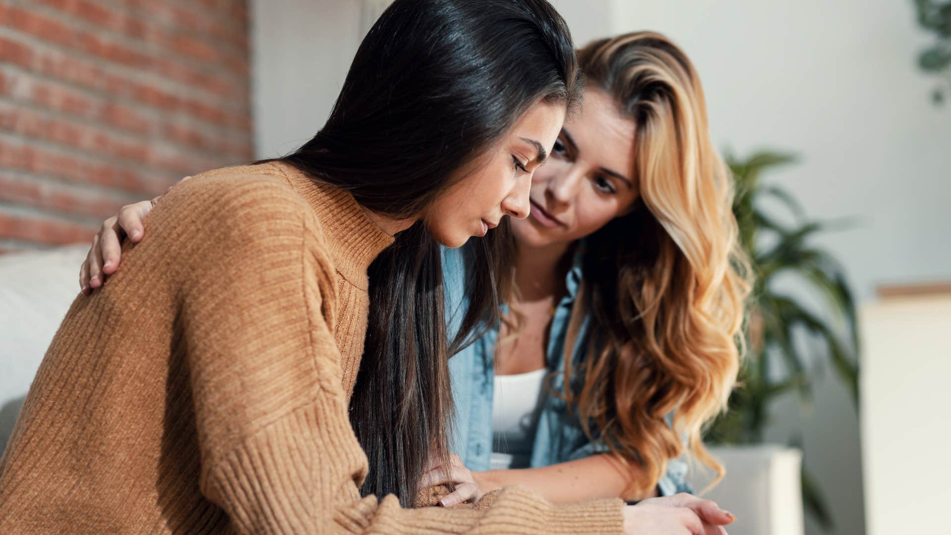 Woman being comforted by a friend looking upset.