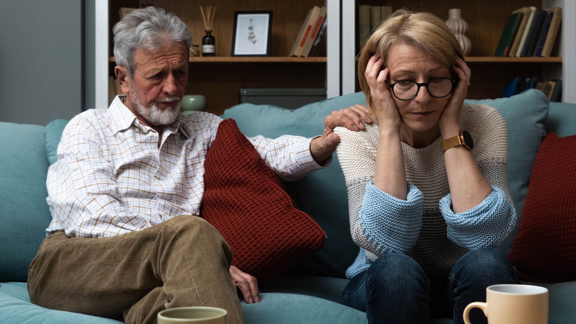 Man comforting his annoyed wife on the couch.