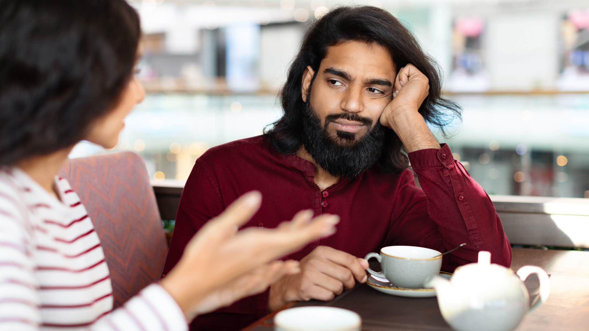 Man looking annoyed while a woman talks to him.