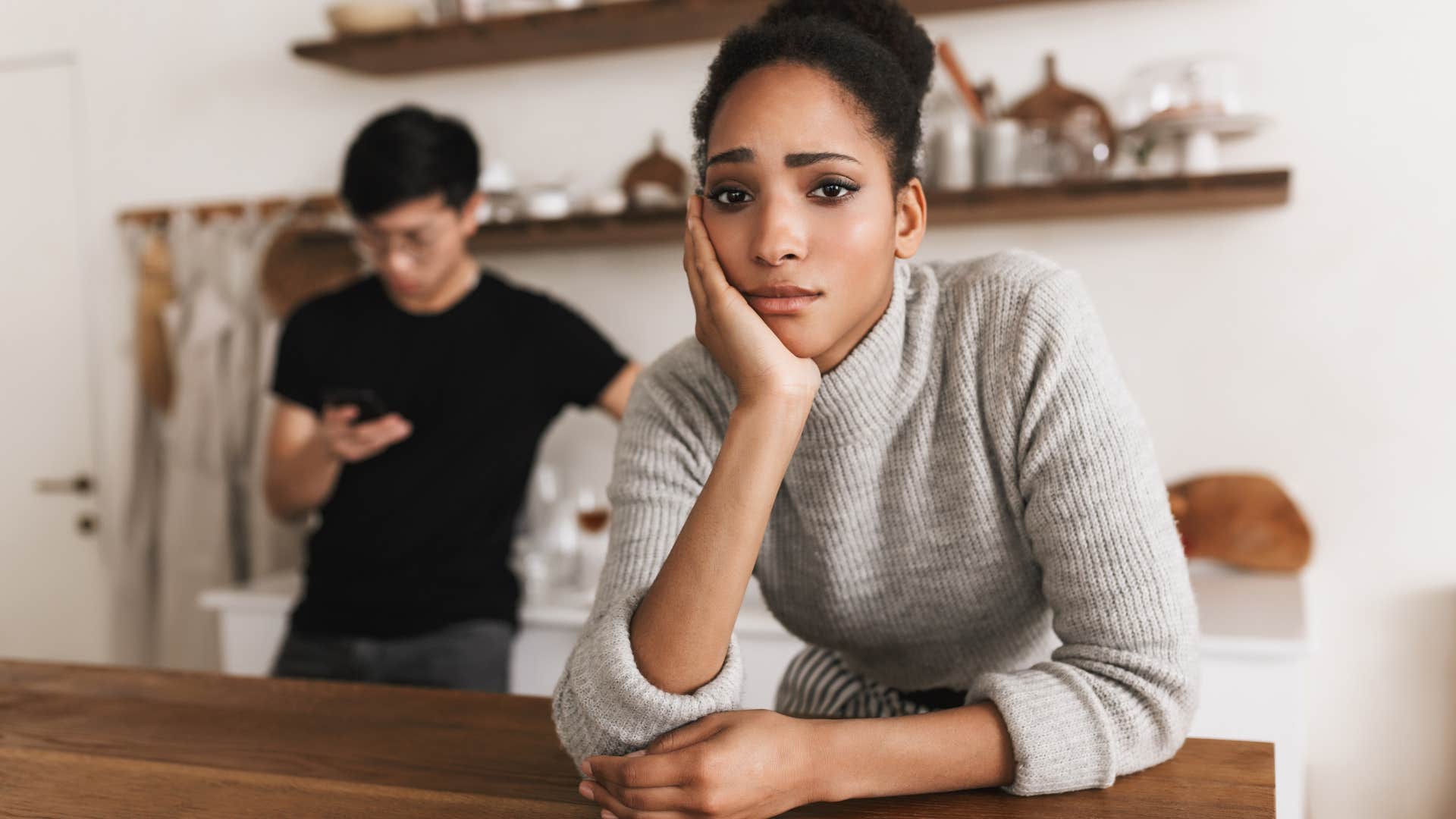 Woman looking upset while her partner texts. 