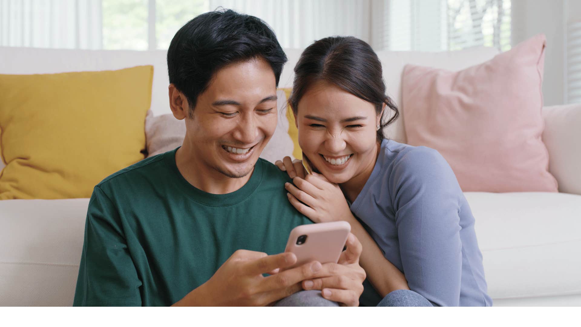 Couple laughs while using mobile device