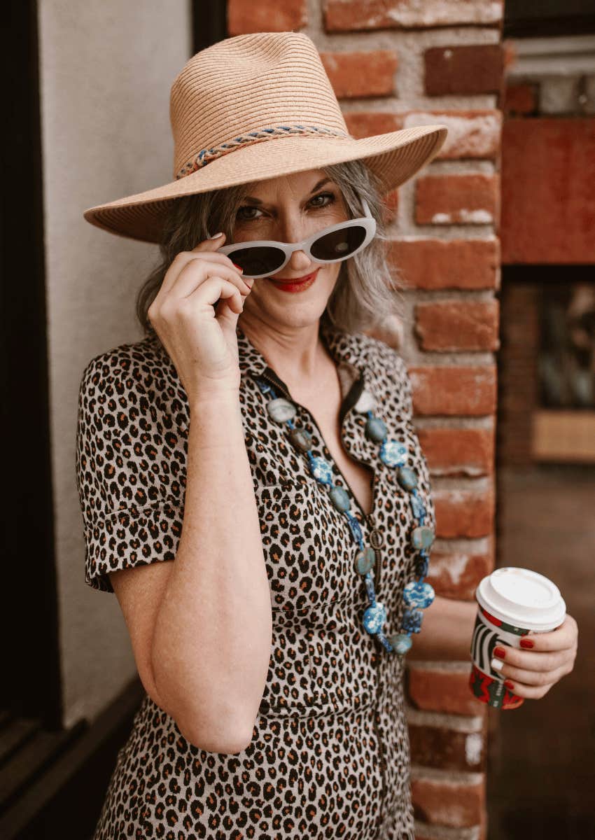 playful older woman wearing sunglasses and sunhat