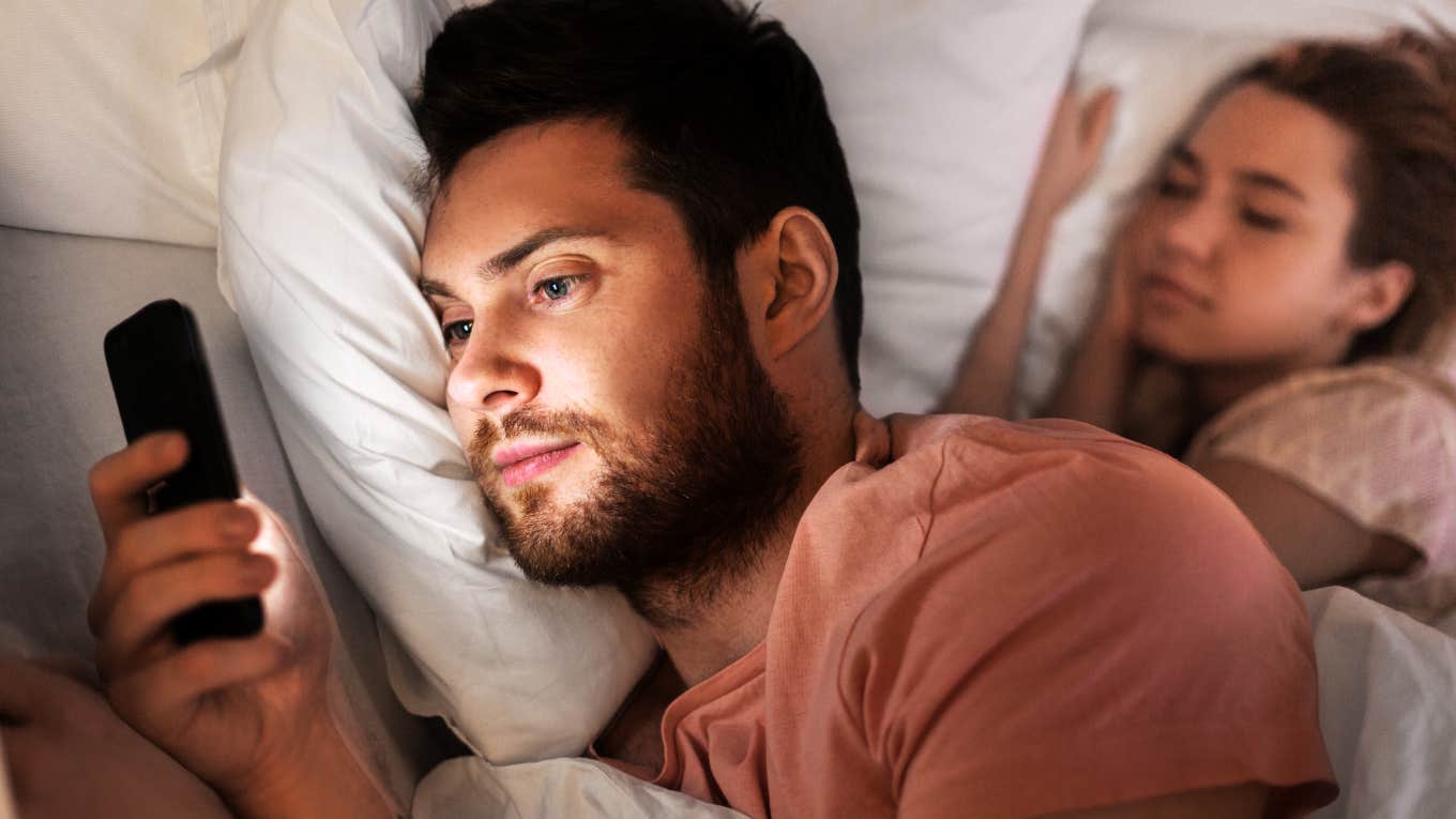 Man emotionally cheating late at night on phone, while wife is in bed next to him.