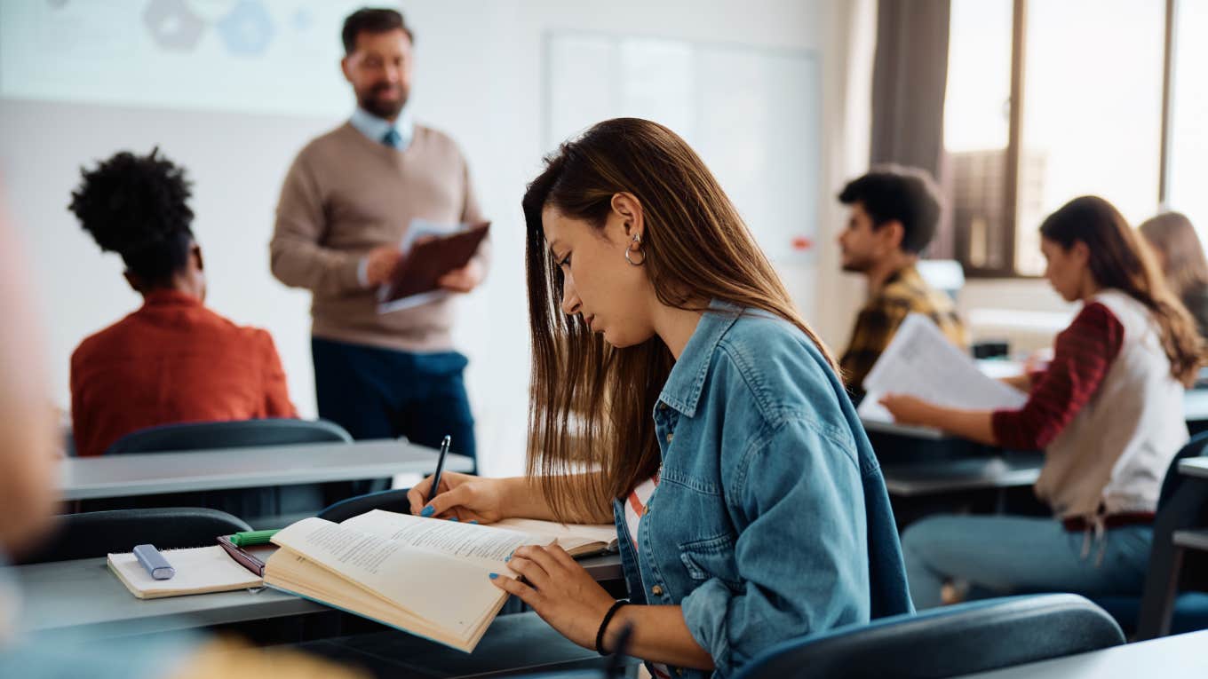 University student writing in her notebook while attending a lecture in the classroom.