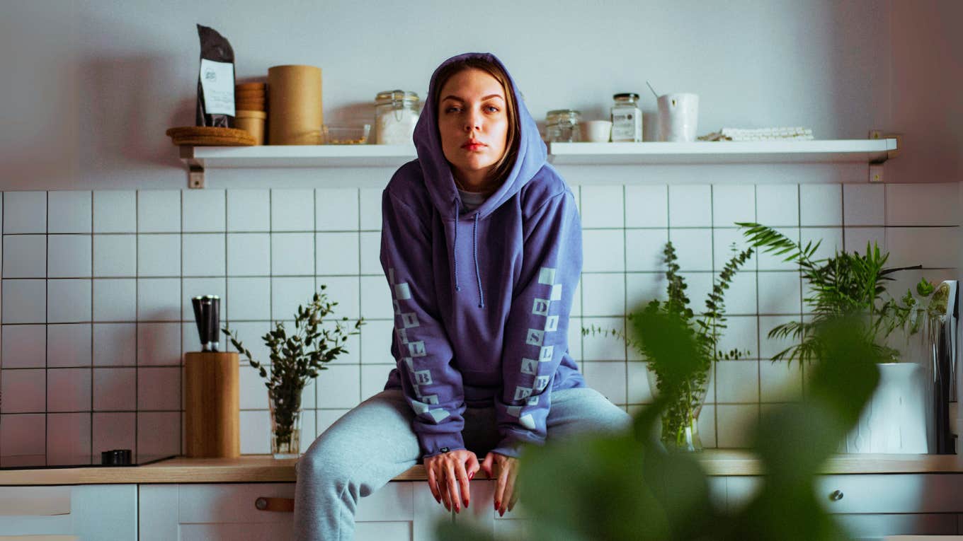 Woman with hoodie up, putting on facade. 