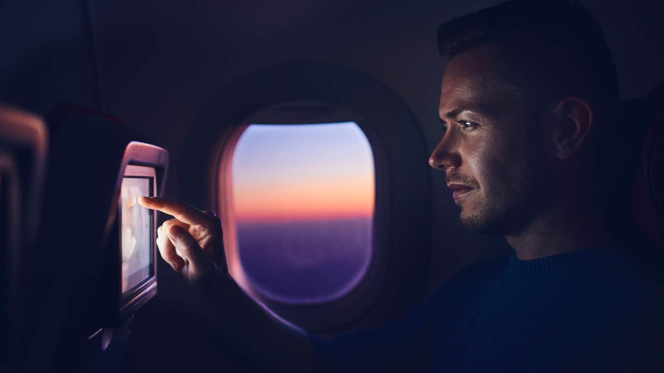 man using in flight entertainment system on plane