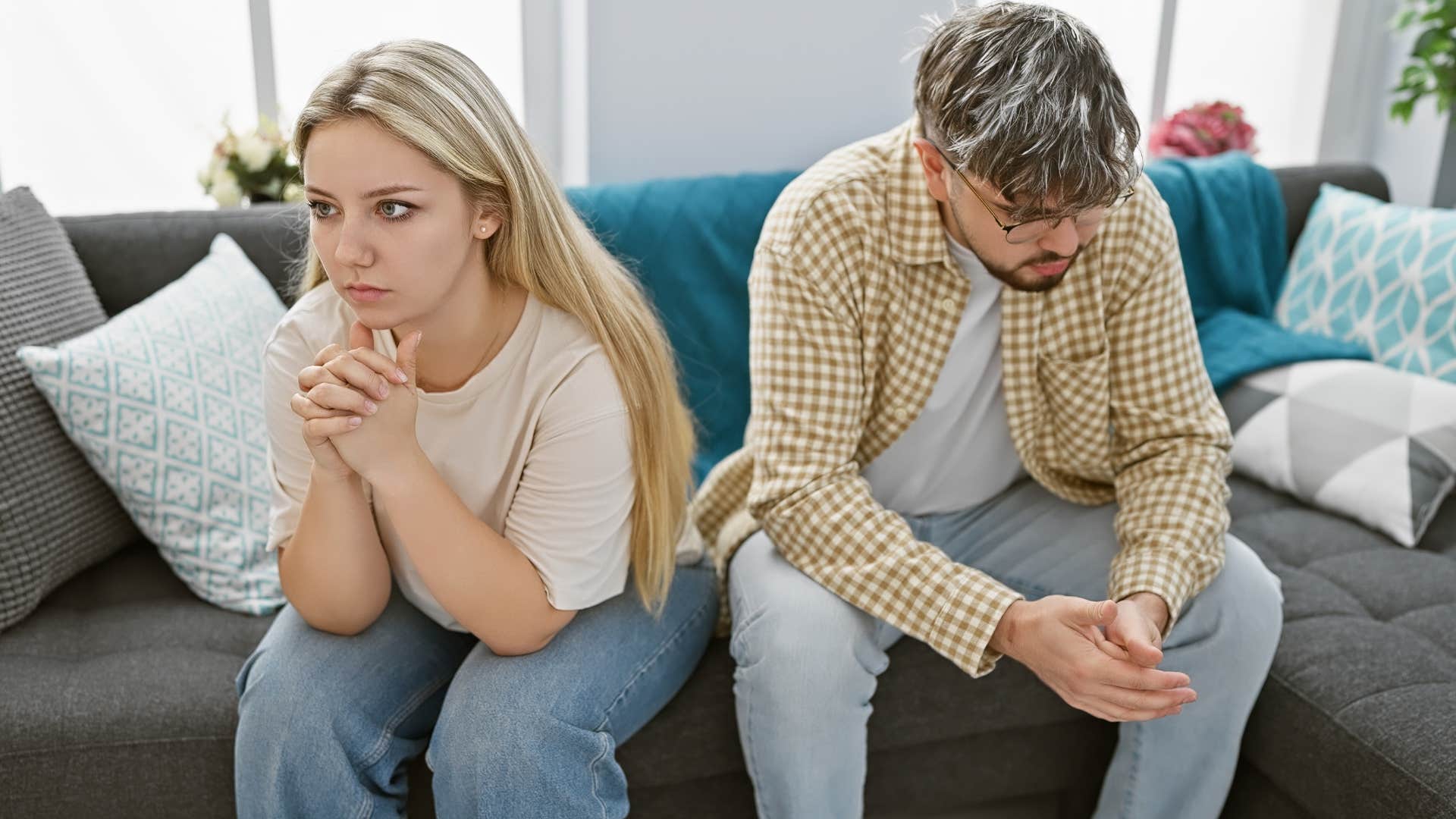 Couple looking upset while sitting on the couch