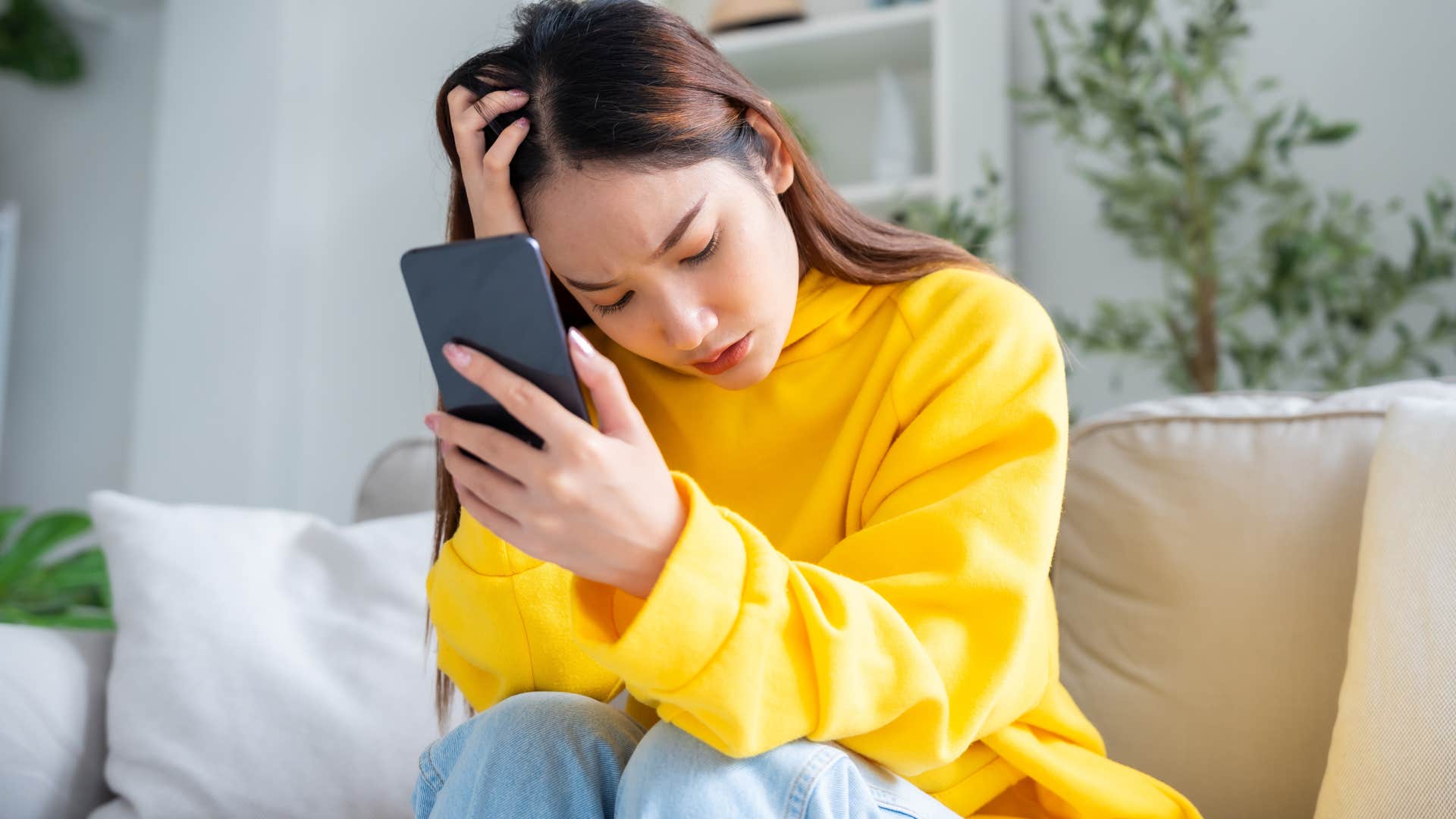 Woman looking upset reading gossip on her phone