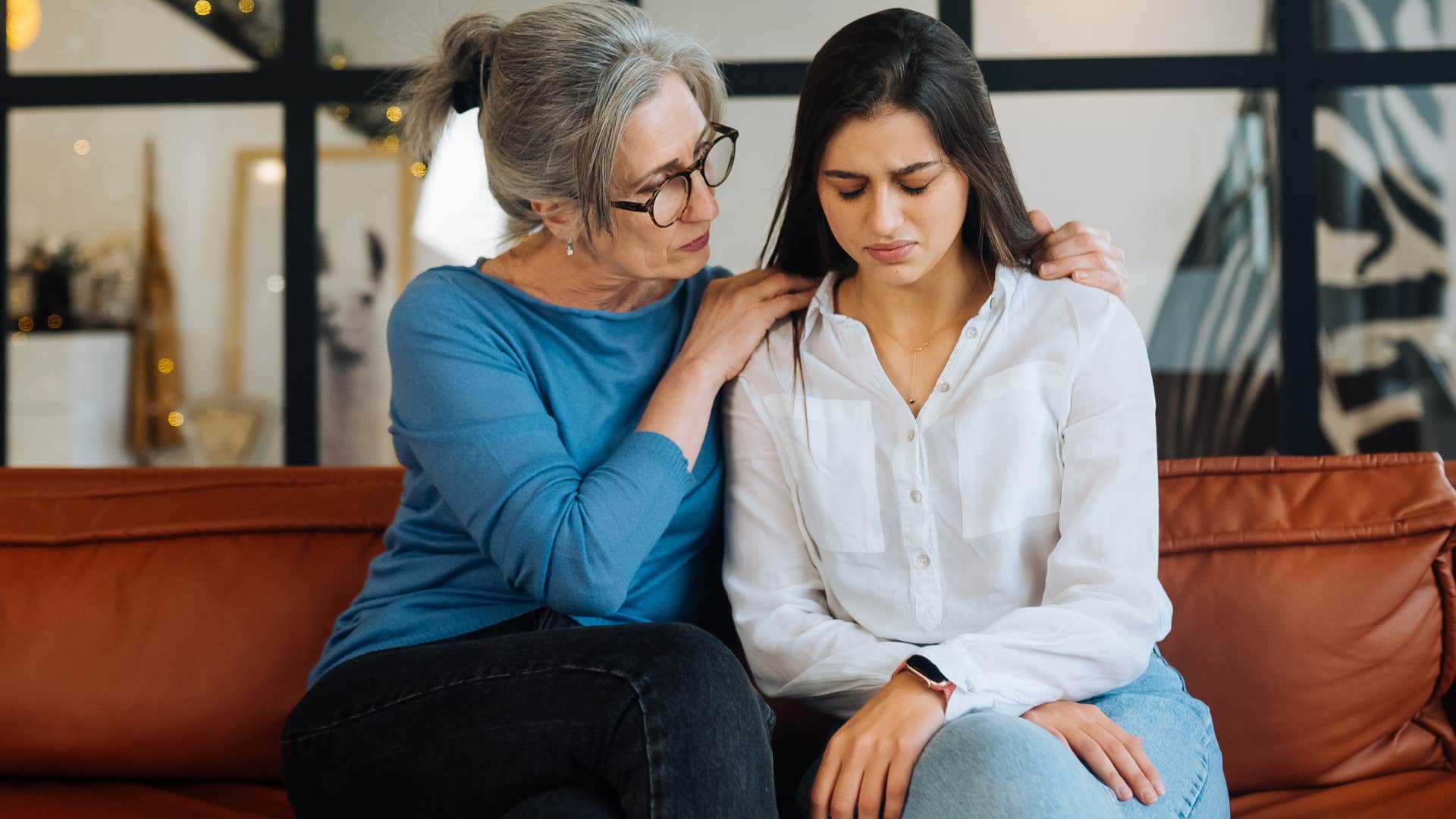 Woman looking sad next to her older mother.