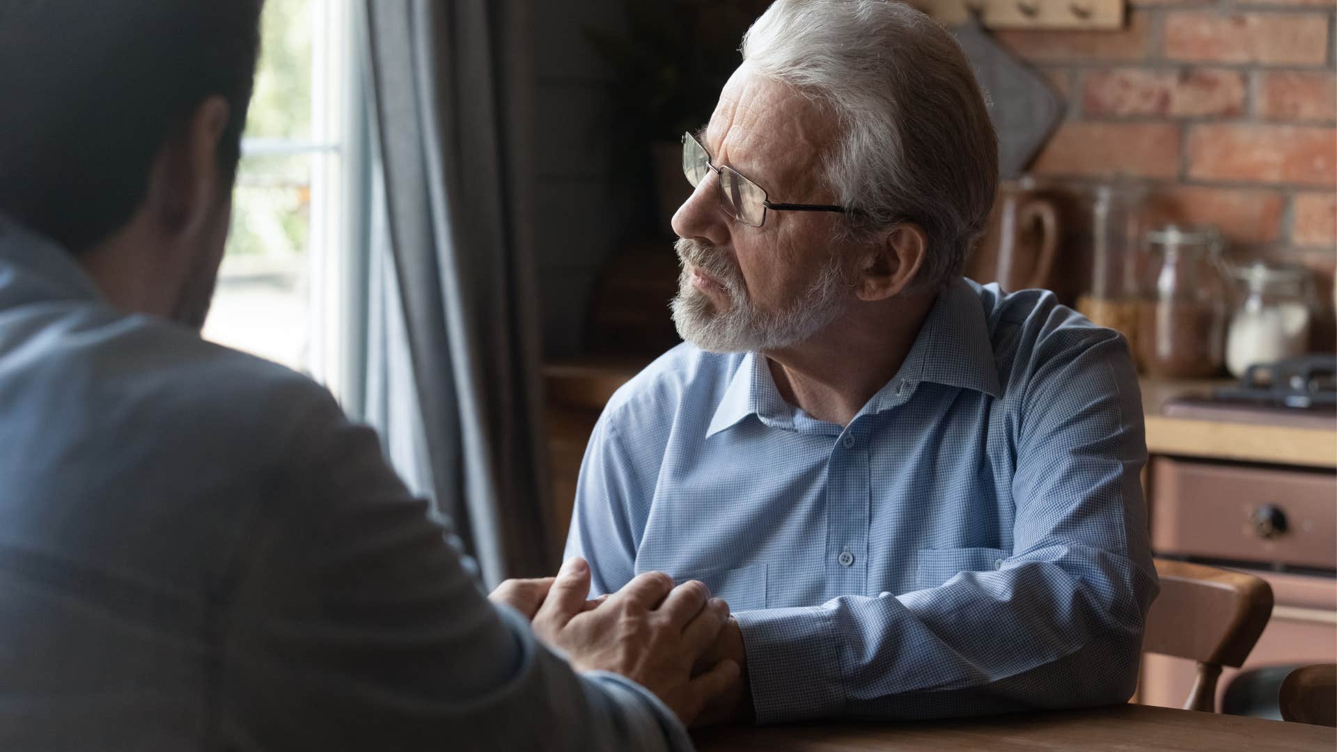 Older man looking away while his son talks to him.