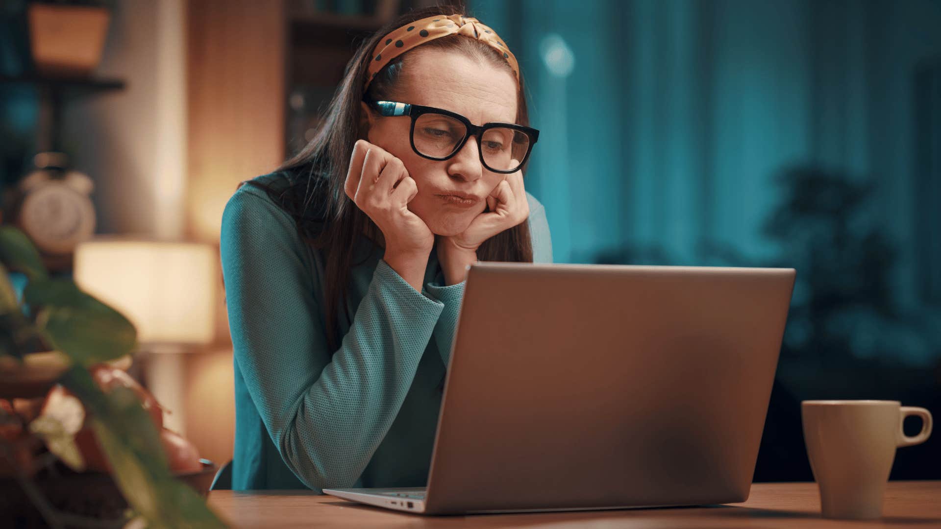 woman looking bored while staring at laptop