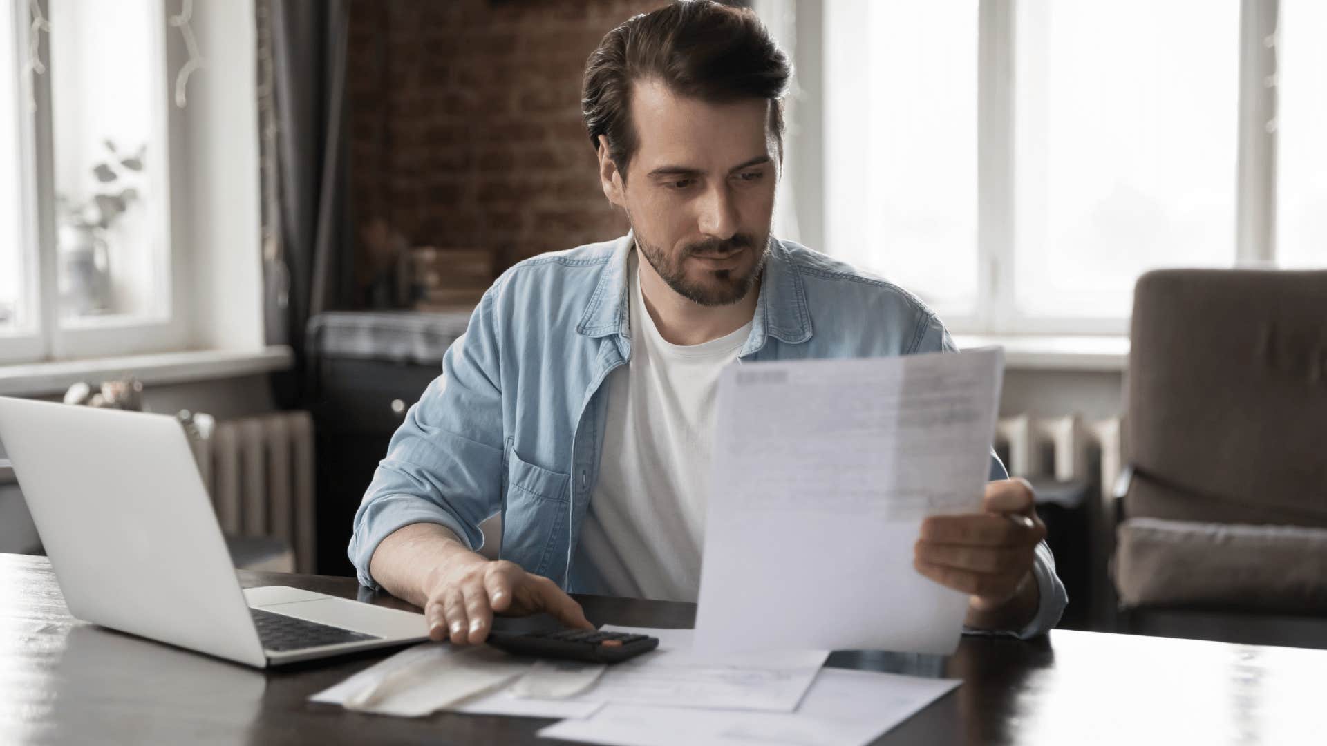 man looking at document while sitting at desk 