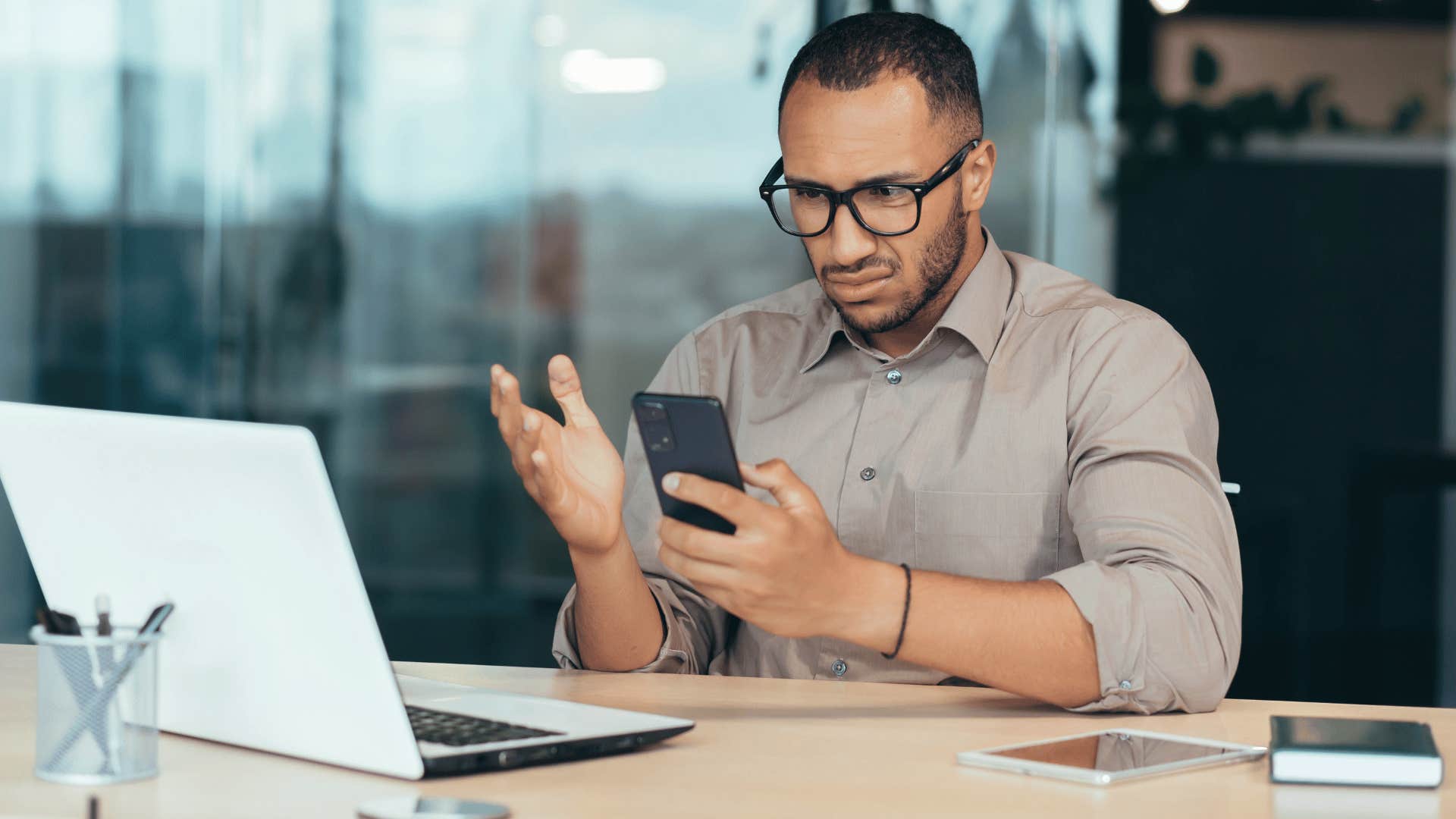 man looking at phone confused