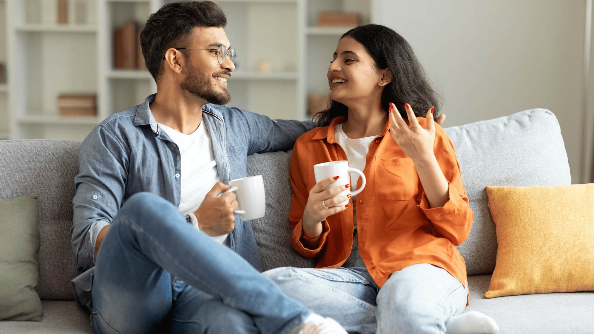 couple chatting and drinking hot beverage on couch