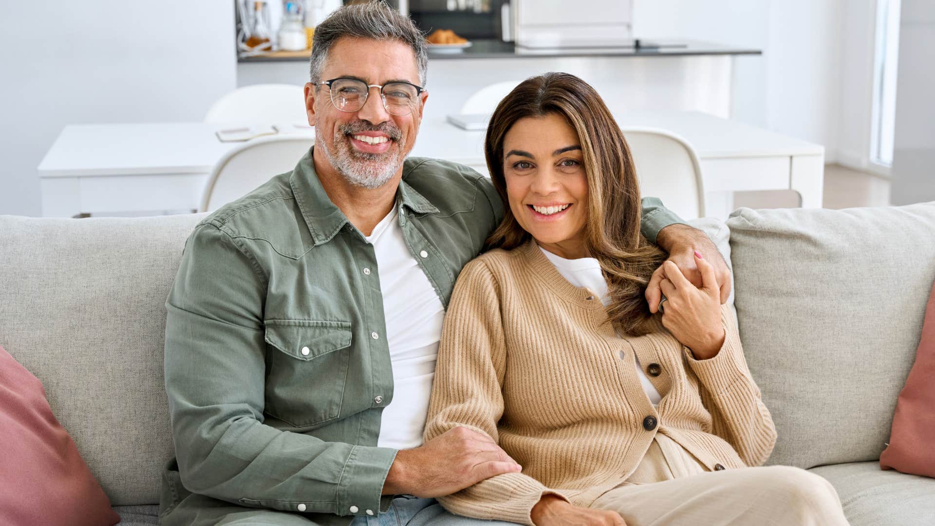 Healthy couple smiling and sitting on the couch.