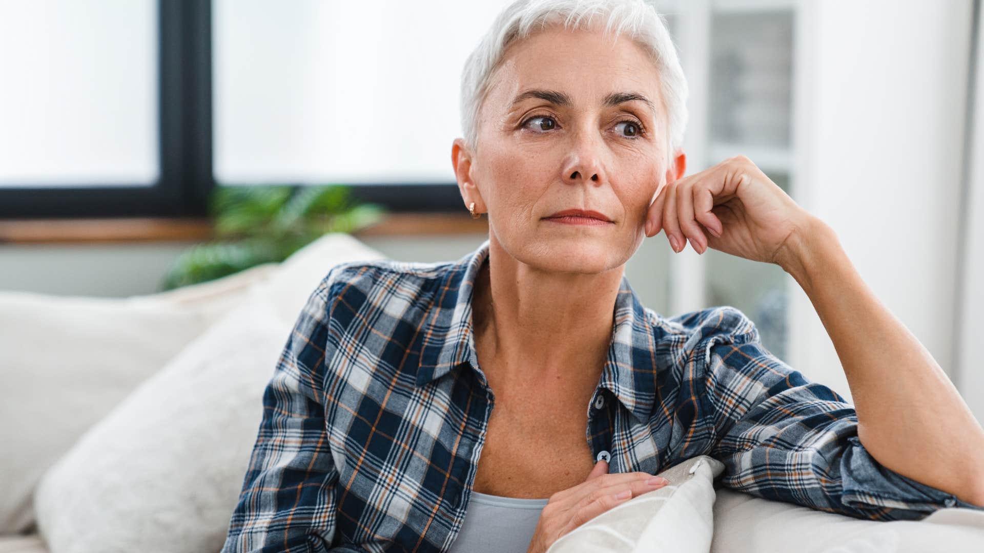 Older woman thinking on her couch.