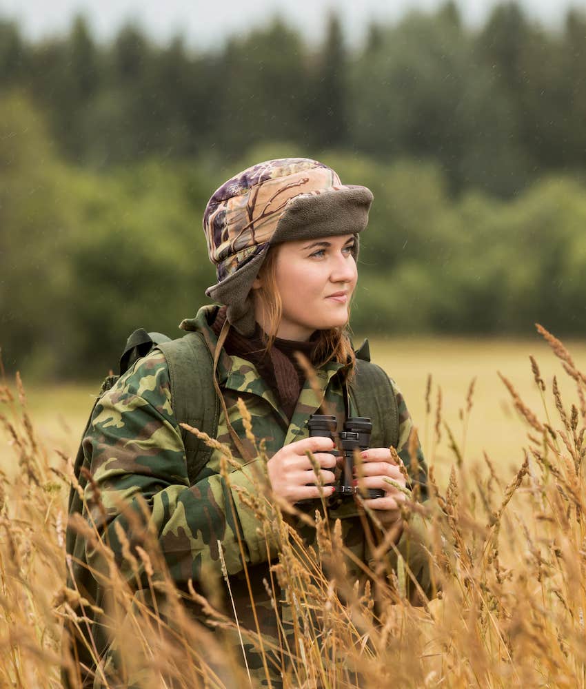 Woman with binoculars in grassy field 