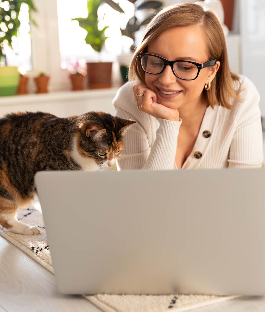 Remote worker on laptop with cat next to her