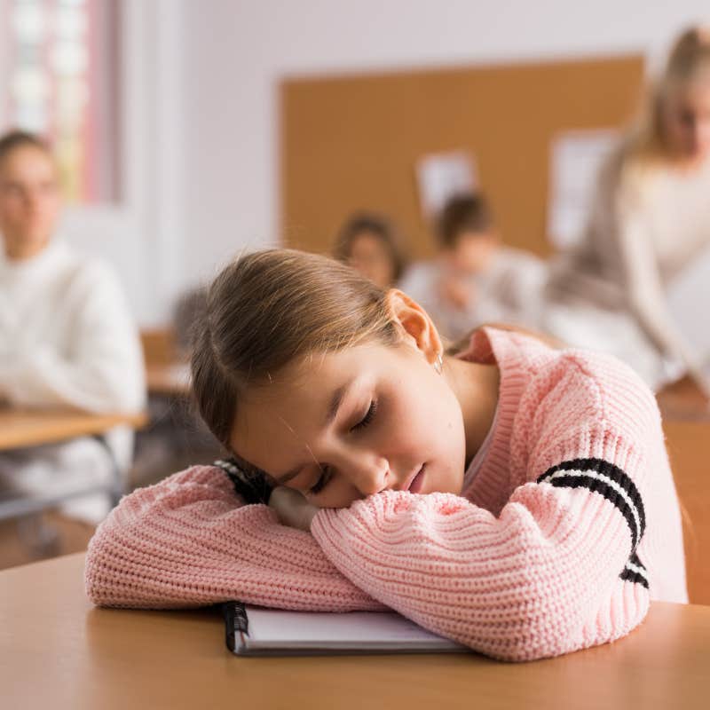 teen girl sleeping with head on desk in class