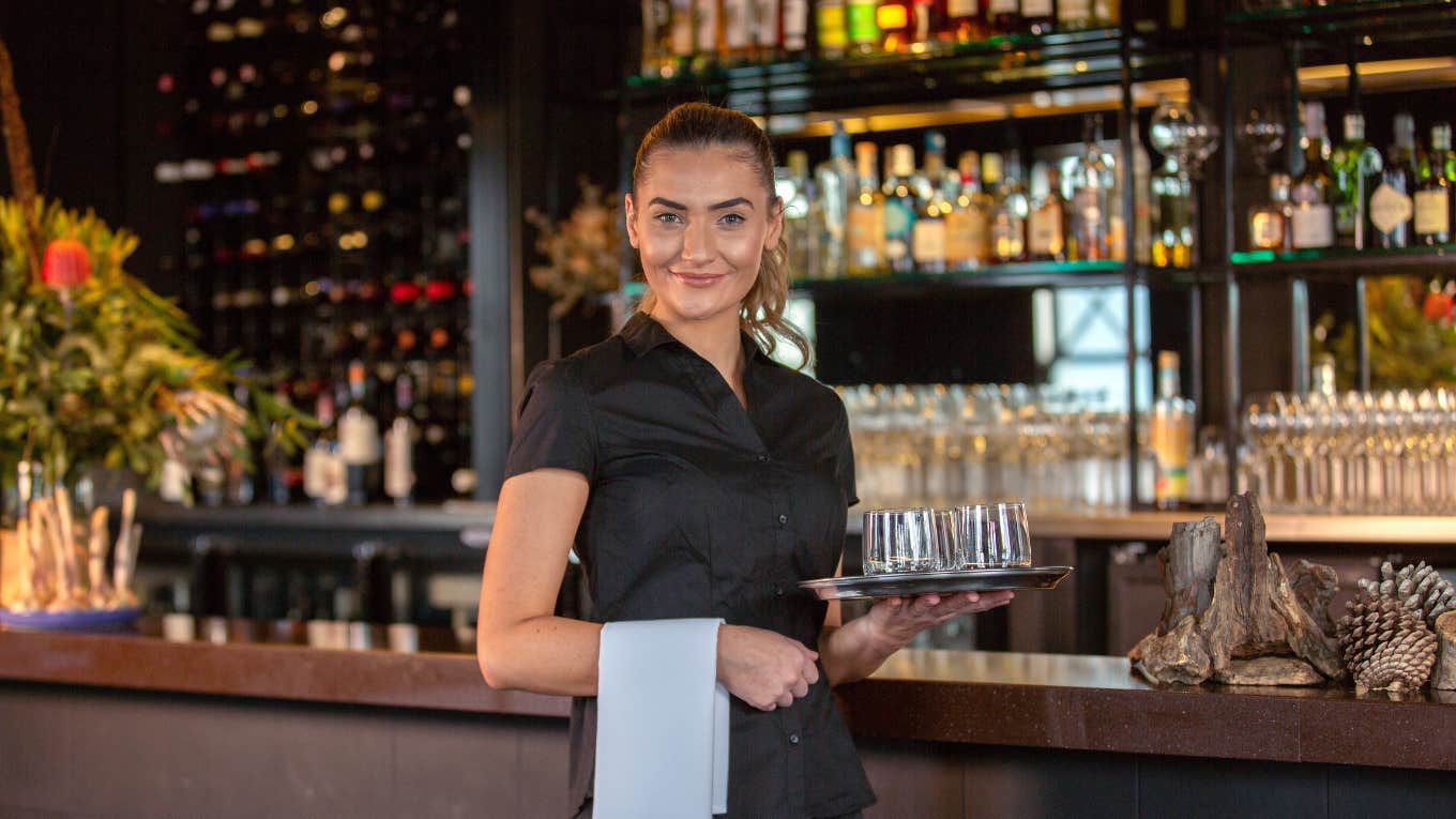 Server smiling while holding water glasses