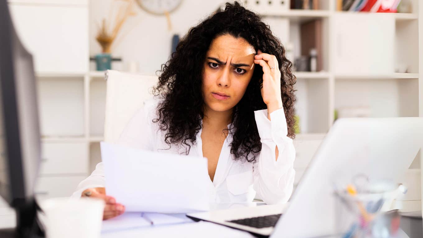 Confused woman at desk, being quiet fired from job. 