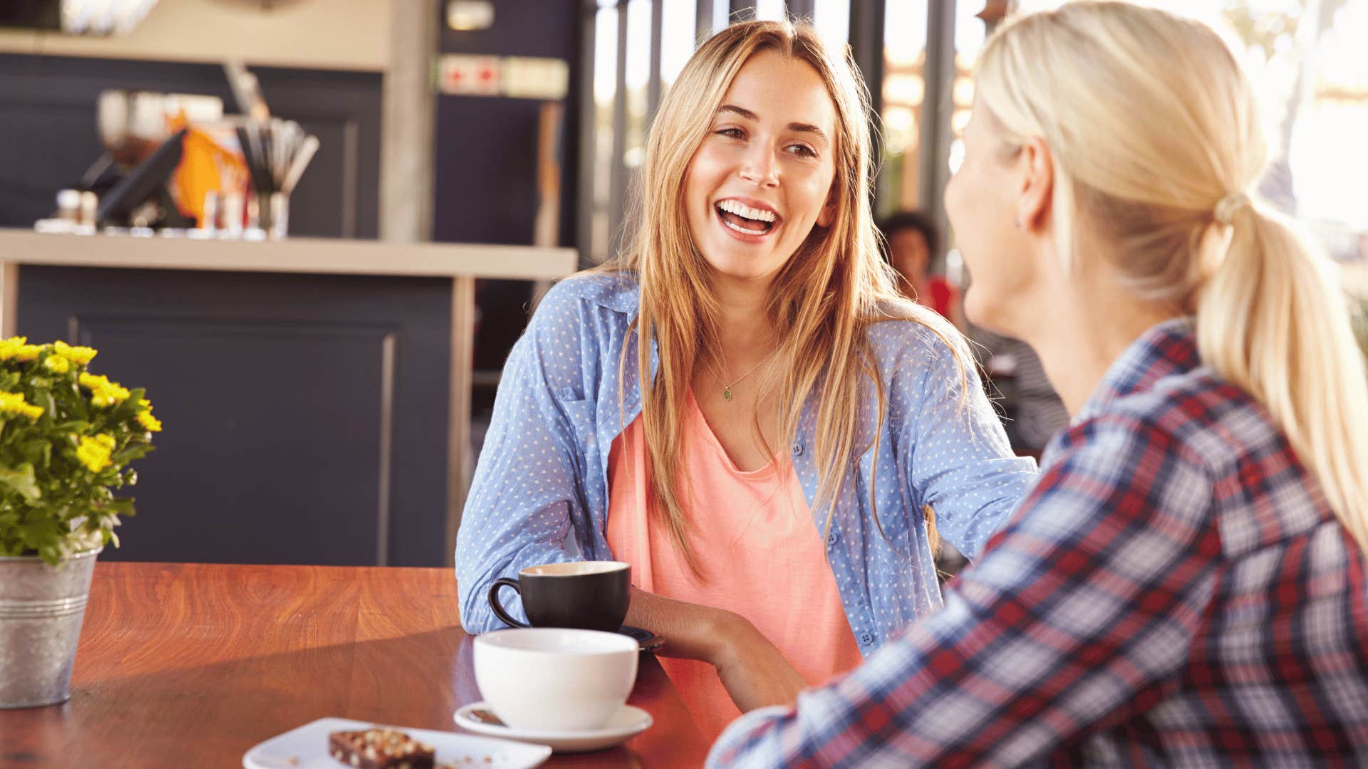 two friends drinking coffee and chatting at coffee shop