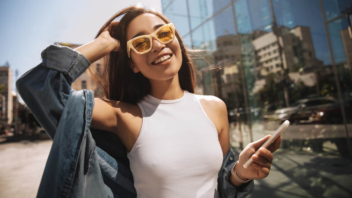 woman outside holding phone with yellow sunglasses