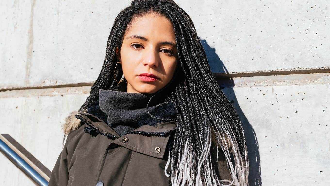 serious looking woman with braids and a green jacket