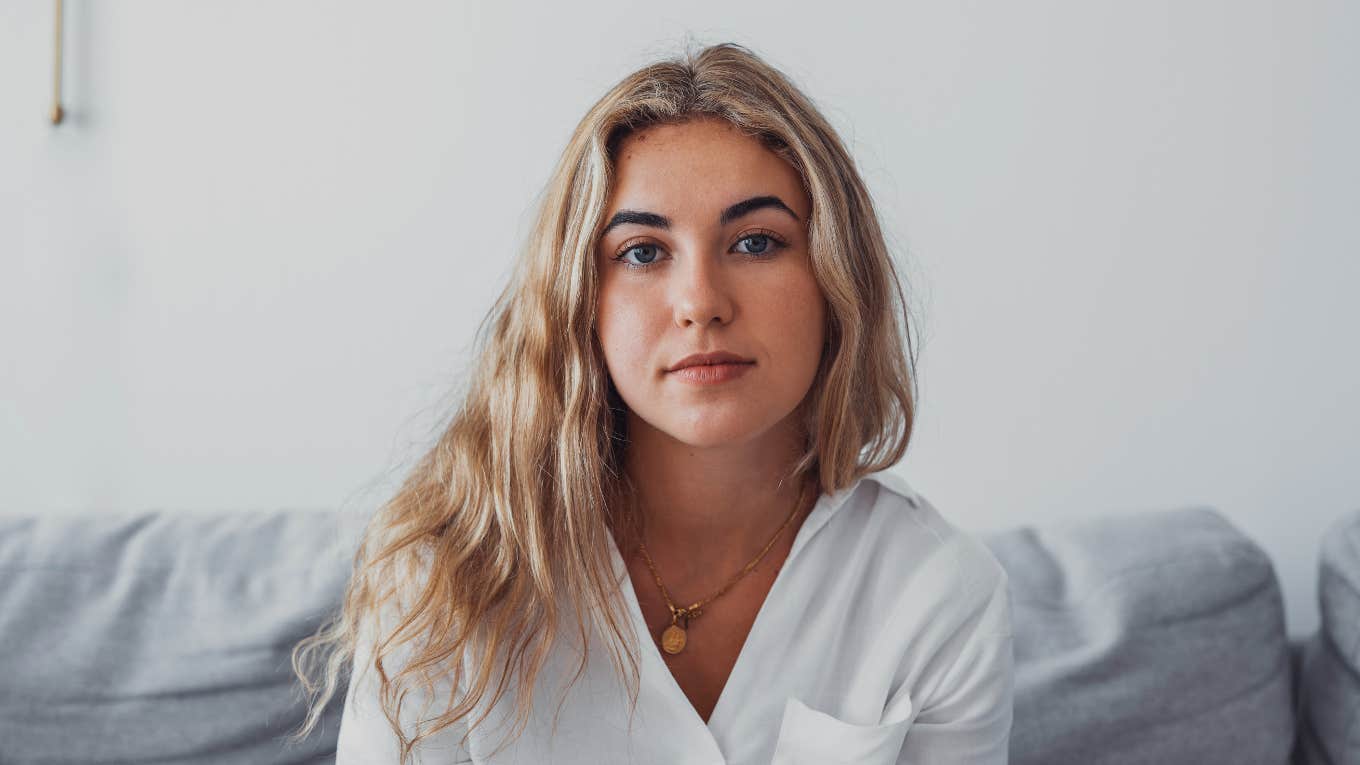 serious young woman sitting on couch thinking about childhood