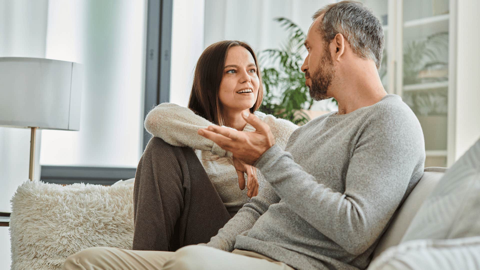 man and woman talking on couch