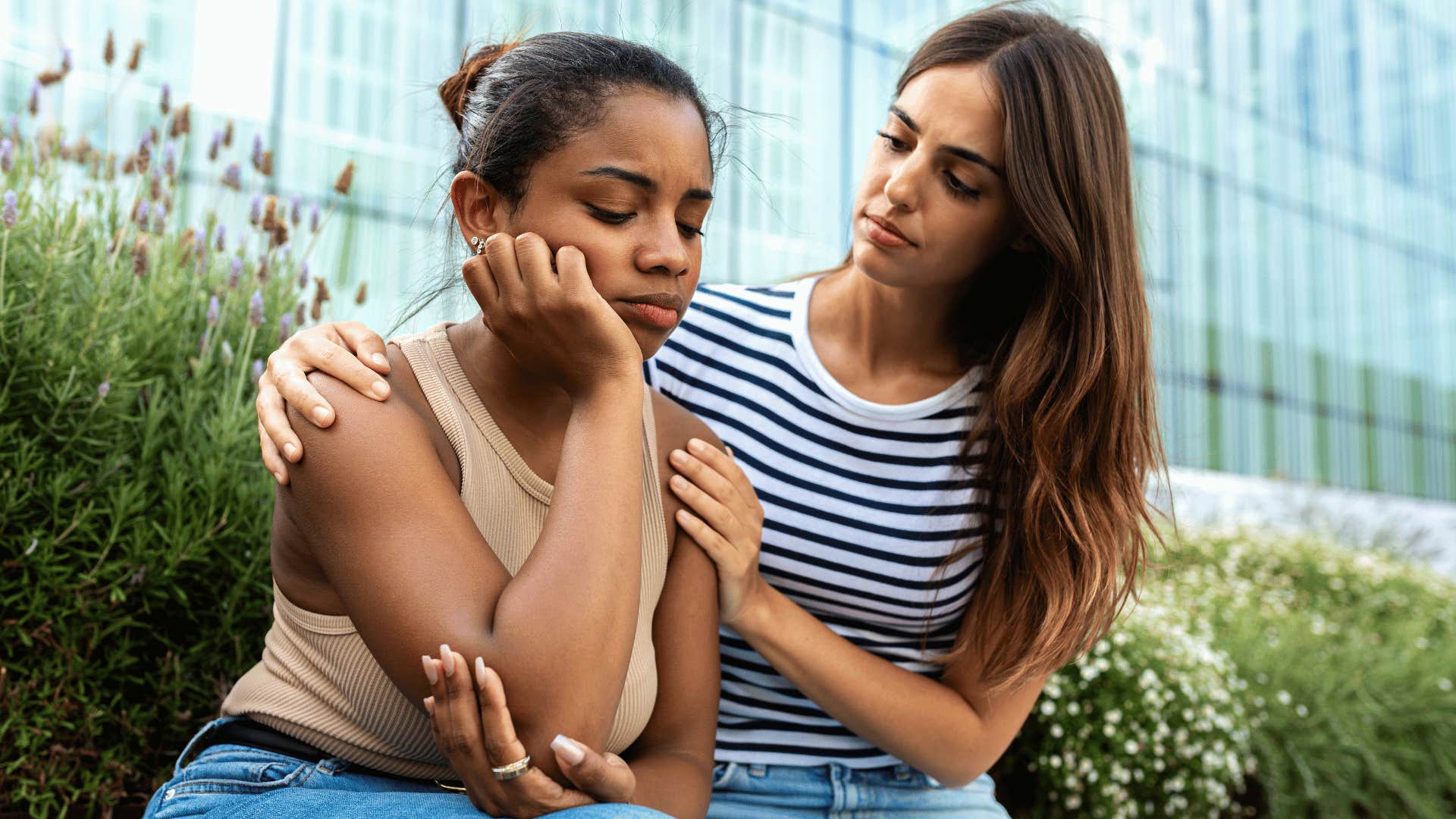 woman comforting upset friend on bench