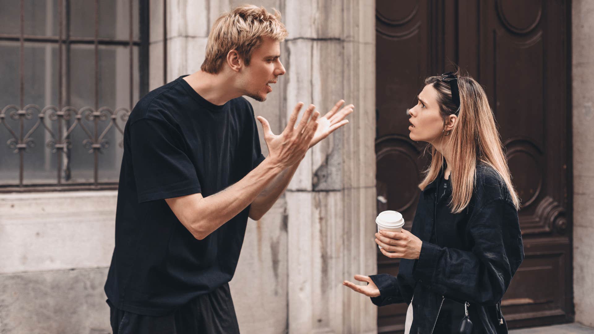 man and woman arguing outside of building 