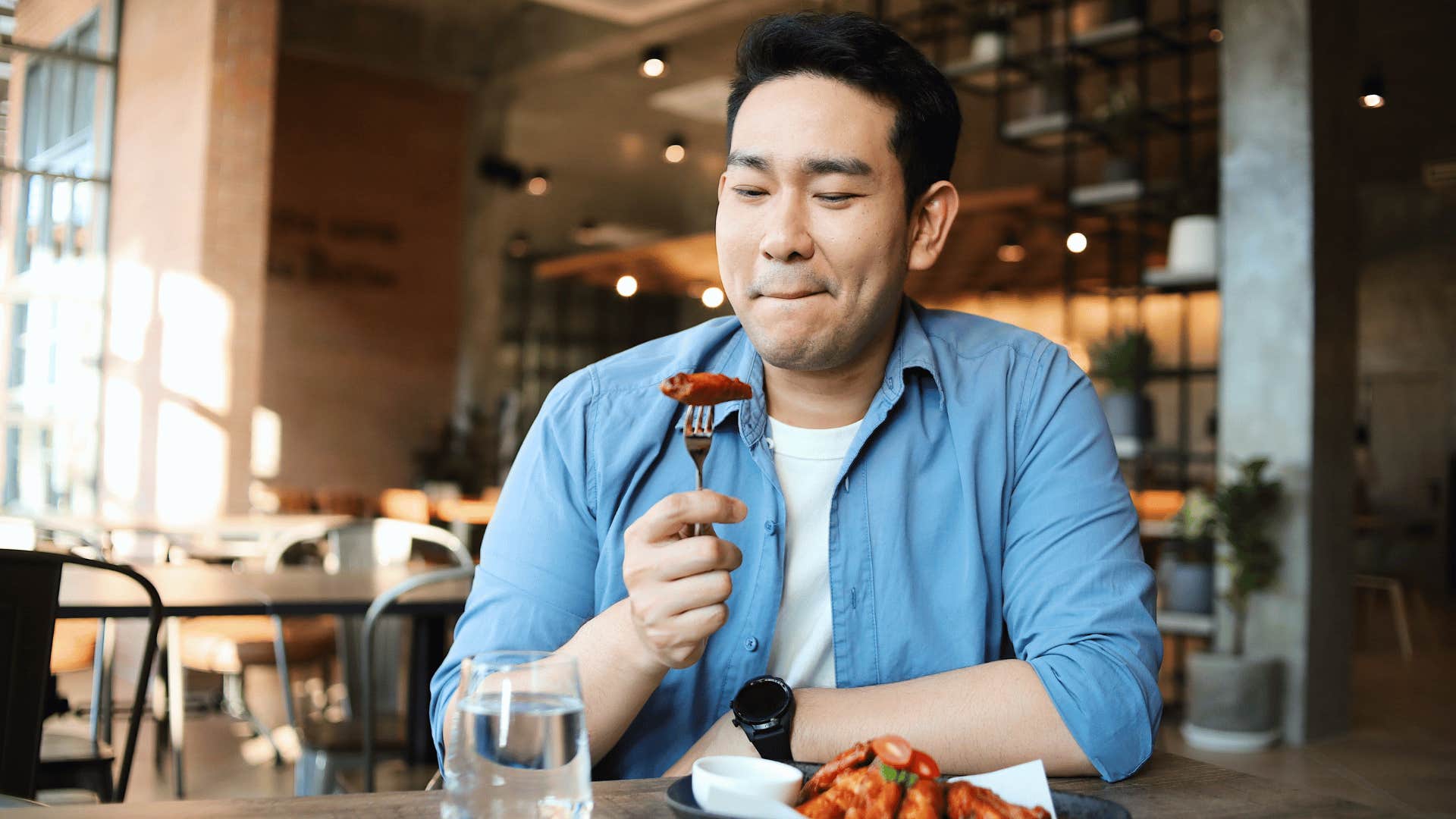 man eating chicken with fork