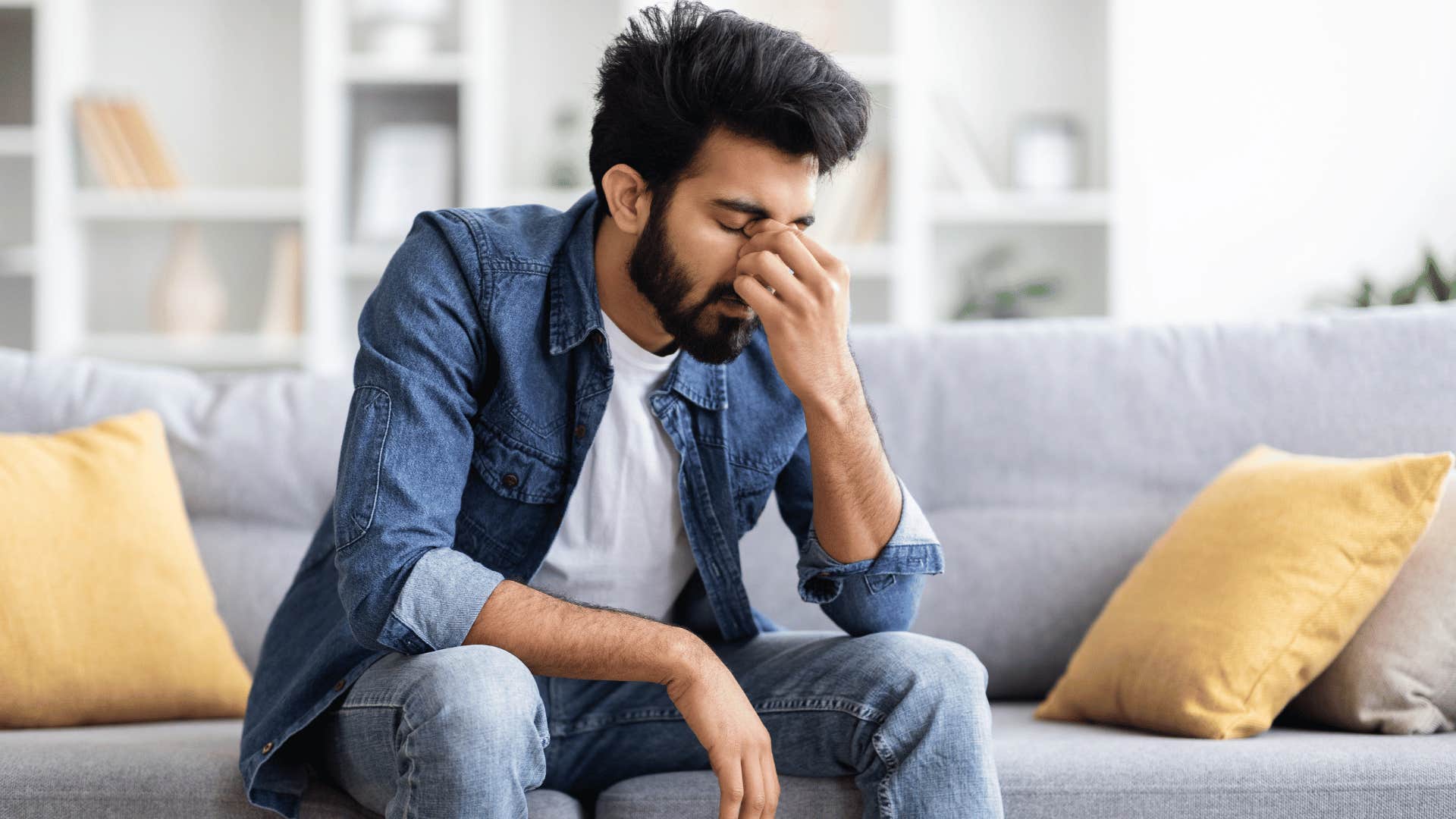 man frustrated while sitting on couch