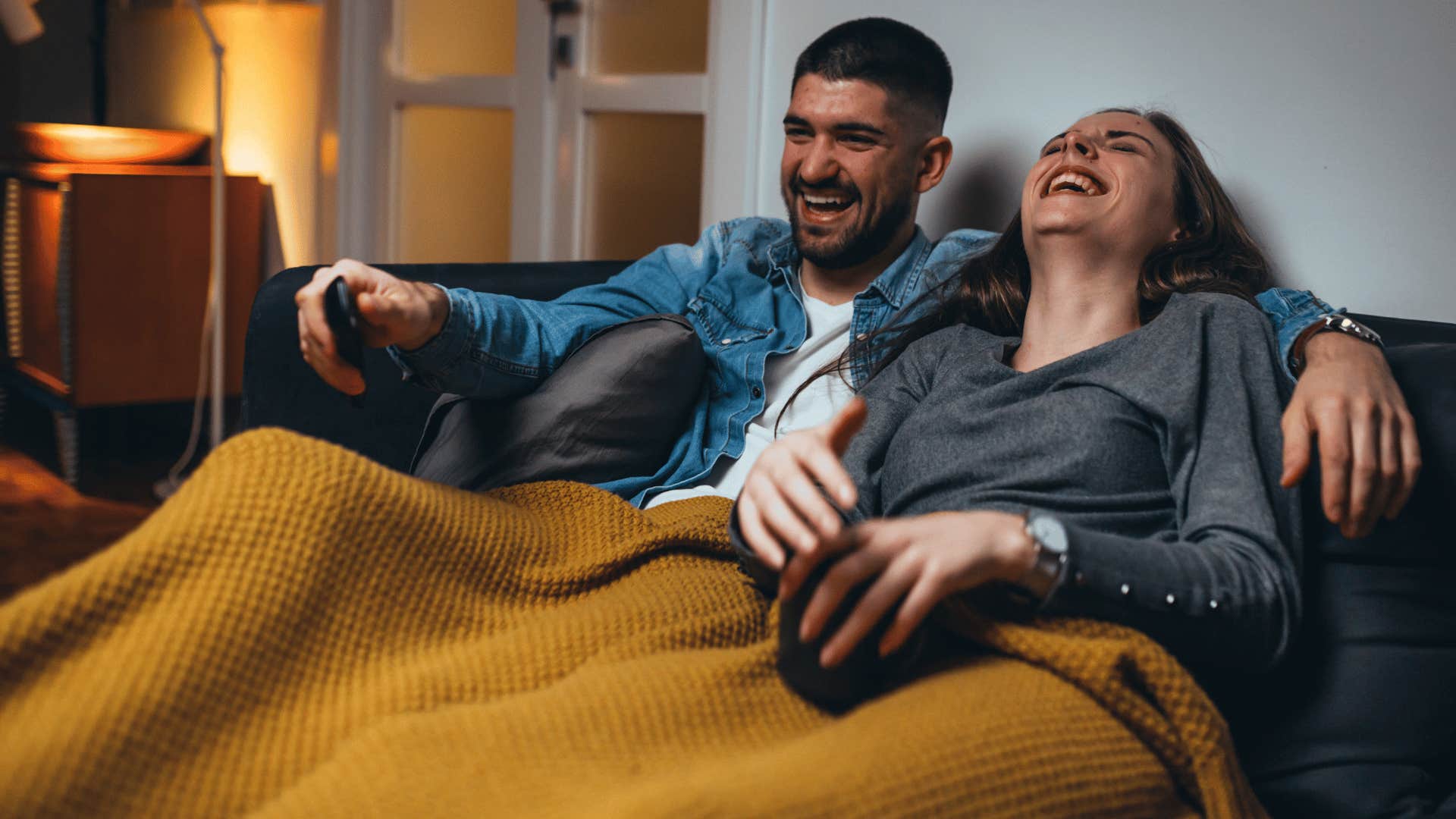 man and woman watching tv and laughing 