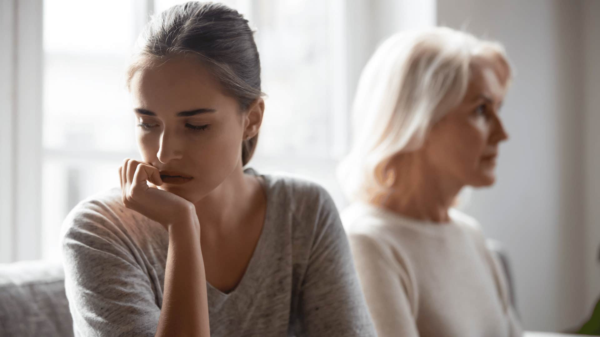 women turning away from older woman as she reflects