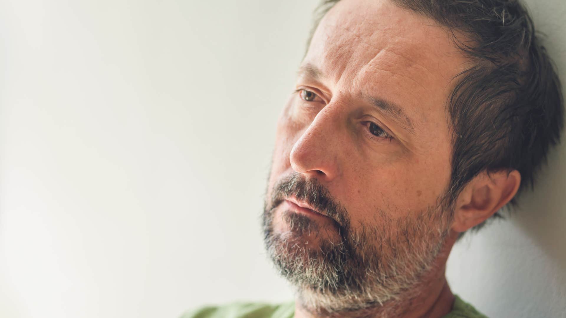 portrait of disconnected man leaning against white wall