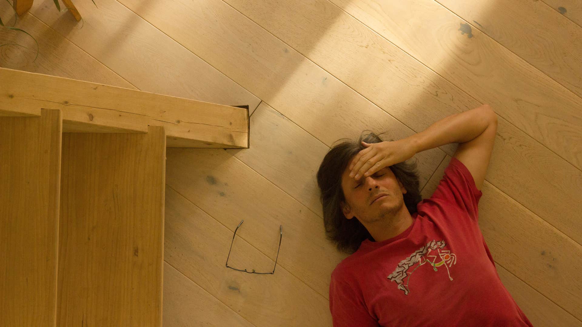 shot of man laying on floor with hand on forehead